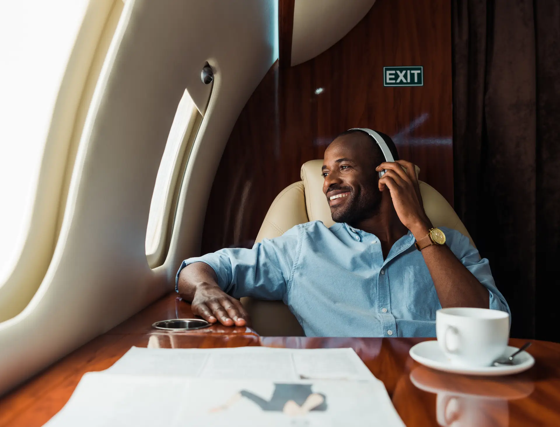A man sits in a private airplane looking out the window wearing headphones.